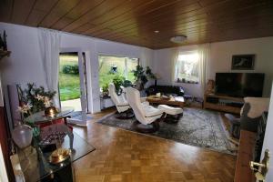 a living room with white chairs and a tv at Haus Hönigblick in Wilnsdorf