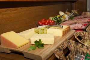 a cutting board with cheese and grapes and other foods at Pension Alpenrose in Zell am See