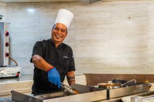 a man wearing a chef hat and gloves preparing food at Casuarina Resort and Spa in Trou aux Biches +84 photos