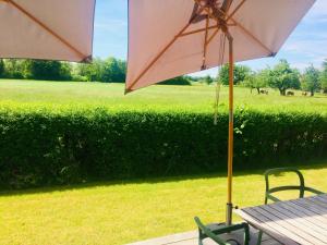 un tavolo con ombrellone e sedie e un campo di simsseeLOFT - Ferienapartments in Baierbach am Simssee a Stephanskirchen