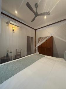 a bedroom with a bed with a ceiling fan at Lagoon View Mawella Villa in Tangalle