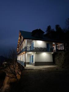a house with blue doors and windows at night at The Blue Mont Sojha Jibhi in Shoja