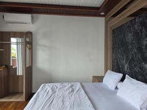 a bedroom with a white bed with a black marble headboard at Probosiwi Resort Syariah in Talunombo