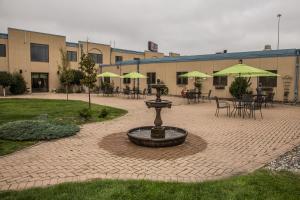a fountain in the middle of a courtyard with tables and umbrellas at Baymont by Wyndham Fargo in Fargo