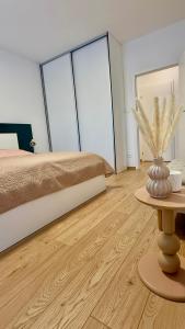 a bedroom with a bed and a table with a vase at Prosperity Apartment s parkovaním in Žilina