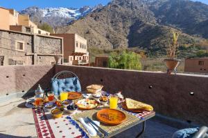 a table with food on a balcony with mountains at Eagle Lodge in Imlil