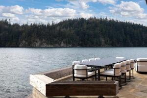 a table and chairs on a dock on a lake at Chuckanut Point Villa 2 Bedroom in Bellingham