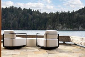 two white chairs sitting on a dock near a lake at Chuckanut Point Villa 2 Bedroom in Bellingham