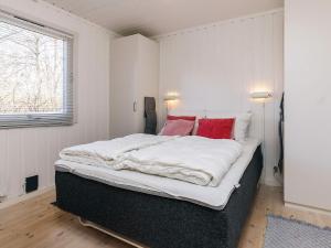 a bedroom with a large bed with white sheets and red pillows at 4 person holiday home in Vejby in Vejby