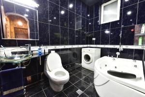 a black tiled bathroom with a toilet and a sink at Tbilisi Art Apartment in Tbilisi City +32 photos