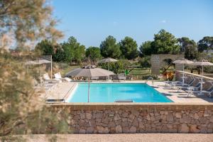 a swimming pool with chairs and umbrellas at Agriturismo Residenza Gemma in Porto Cesareo