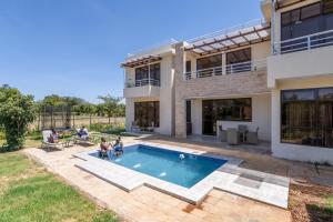 a villa with a swimming pool in front of a house at OSOTUA Villa 18 Home Hotel Nanyuki 7 Bedrooms 14 Guests in Nanyuki