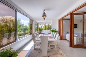 a dining room with a white table and chairs and large windows at OSOTUA Villa 18 Home Hotel Nanyuki 7 Bedrooms 14 Guests in Nanyuki