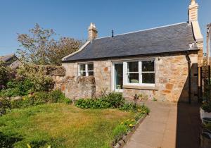 a stone house with a window and a yard at Lochburn Cottage in Elie