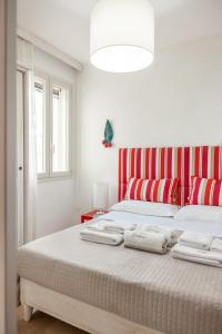 a white bedroom with a large bed with red and white stripes at Agriturismo Residenza Gemma in Porto Cesareo +74 photos