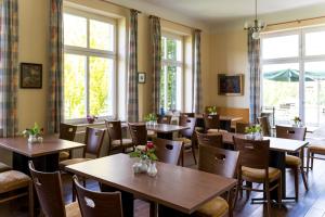 a restaurant with wooden tables and chairs and windows at Gutshaus Barkow in Barkhagen