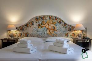 a bed with towels on it with a painting on the wall at Hotiday Taormina Baia in Taormina