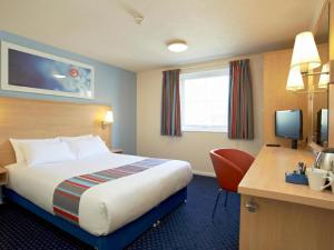 a hotel room with a bed and a desk at Travelodge Widnes in Widnes