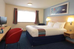 a hotel room with a bed and a desk and a television at Travelodge Widnes in Widnes