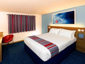 a hotel room with a bed and a red chair at Travelodge Widnes in Widnes +2 photos