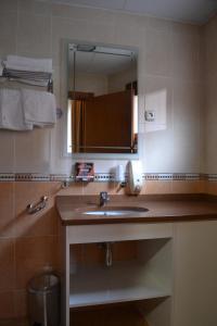 ein Bad mit einem Waschbecken und einem Spiegel in der Unterkunft Hostal Restaurante El Castillo in Alcorisa