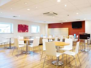 a dining room with tables and white chairs at Travelodge Middlesbrough in Middlesbrough