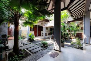a courtyard with palm trees and a building at RedDoorz @ Soekarno Hatta 2 in Malang