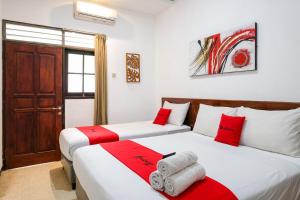 two beds in a room with red and white at RedDoorz @ Soekarno Hatta 2 in Malang