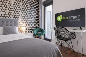 a bedroom with a bed and a desk and a tv at Eco Smart Apartments Erlangen in Erlangen