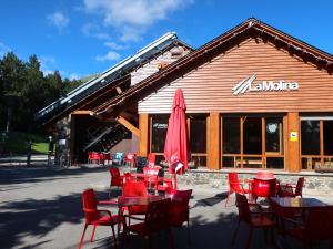 a restaurant with tables and chairs and a red umbrella at Loft 4 personas en La Molina in La Molina