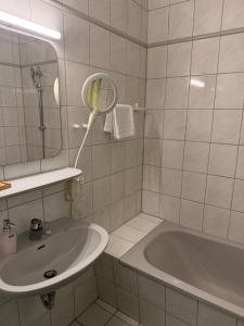 a bathroom with a sink and a tub and a mirror at Haus Hotel Inter in Buxtehude