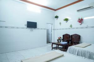 a room with two beds and a table and a tv at Nhà Nghỉ Hiếu Thuận in Nhơn Trạch