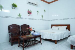 a bedroom with a bed and a table and a chair at Nhà Nghỉ Hiếu Thuận in Nhơn Trạch