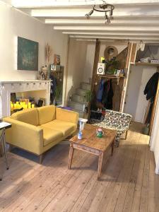 a living room with a yellow couch and a coffee table at Joli maison de bourg in Savennières