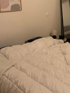 a white comforter laying on top of a bed at Le Cocoon Elite in Beynost