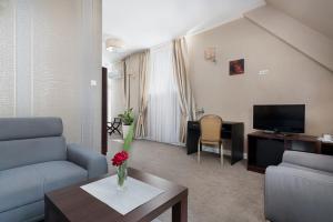 a living room with a couch and a tv and a table at Hotel Pod Kasztanami in Lublin