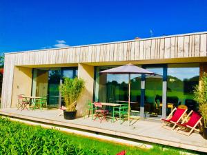 una casa con un ponte con sedie e un ombrellone di simsseeLOFT - Ferienapartments in Baierbach am Simssee a Stephanskirchen Altre 82 foto