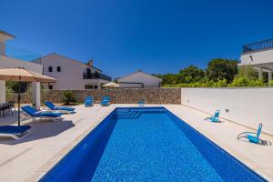 a swimming pool in a yard with chairs and a house at Holiday house DAN with private pool in Kras