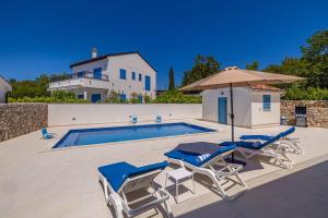 a swimming pool with two chairs and an umbrella at Holiday house DAN with private pool in Kras
