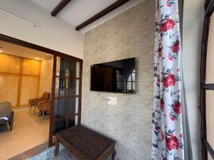 a stone fireplace with a television on a wall at The Doghouse in Dehradun