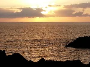 una puesta de sol sobre el océano con un barco en la distancia en Eurosant Playas, en Playa de San Juan