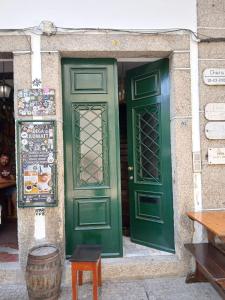 two green doors on a building with a table and a barrel at Casa Kilowatt - Amarante in Amarante