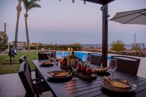 a wooden table with food and wine glasses and an umbrella at Villa Hera in Ayios Theodhoros
