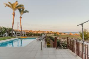 a swimming pool with a bench and palm trees at Villa Hera in Ayios Theodhoros