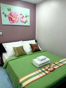 a bedroom with a large bed with a green blanket at 9 Home Phuket in Ban Rangeng