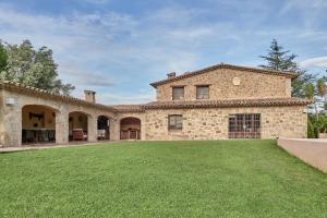 an exterior view of a large stone house with a yard at LuxRural Montserrat | Piscina con Vistas Únicas in Marganell