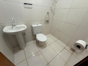 a white bathroom with a toilet and a sink at Kitnet Econômica e Funcional in Campo Grande +7 photos