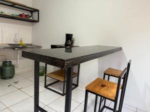 a kitchen with a table and two stools at Kitnet Econômica e Funcional in Campo Grande