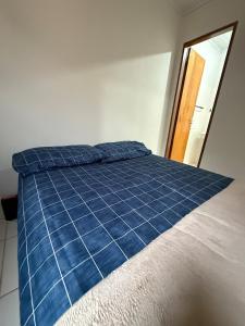 a bed with a blue comforter in a room at Kitnet Econômica e Funcional in Campo Grande