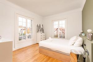 a white bedroom with a bed and two windows at MISVA KEYWEEK Architect-designed flat in Biarritz with garden in Biarritz